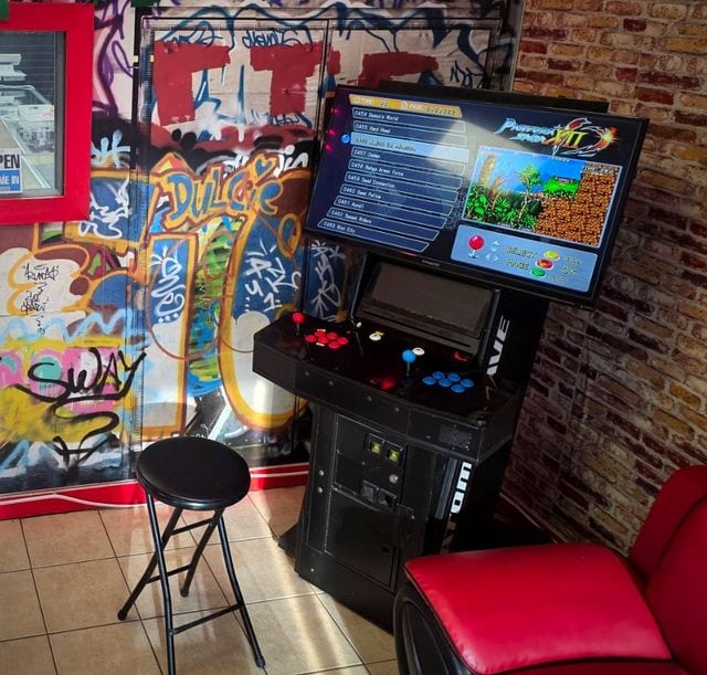 An arcade cabinet beside the lounge's graffiti wall.