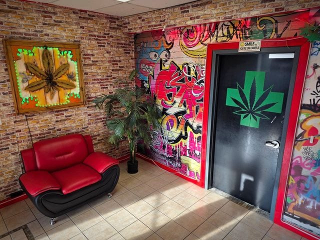 The waiting lounge: exposed brick, a red leather chair, a backlit leaf artwork and a graffiti mural.