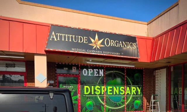 The Attitude Organics storefront on N Rockwell Avenue, gold lettering on a black awning above a lit window display.