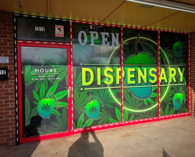 The dispensary window display at 1512, lit green, with opening hours of 9am to 10pm.